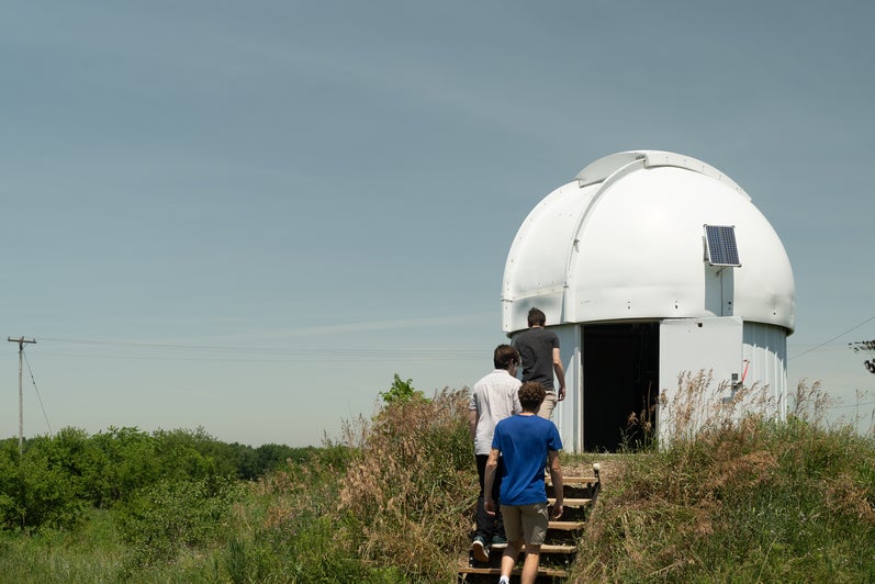 Three people walking into an observatory 