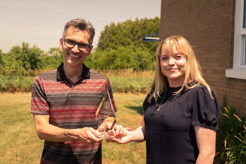 Dr Metchev accepting the award for Impact in Research from Kate Baker 