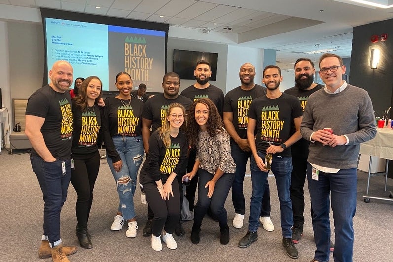 Intuit African Ancestry Network of team members posing for a group photo wearing Black History Month t-shirts.