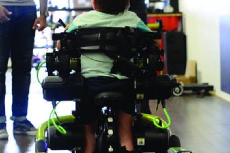 A back view of Noah using the Trexo to walk.