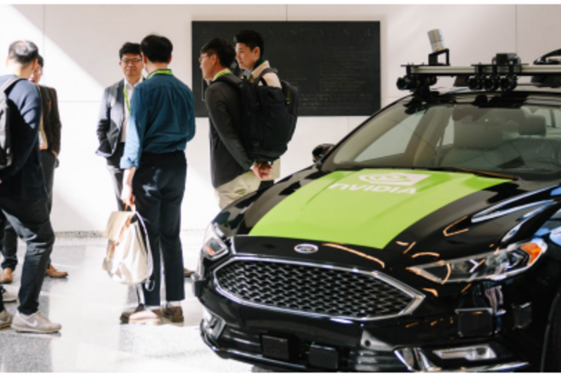 Group of co-op students standing in a circle next to a NVIDIA green and black car.