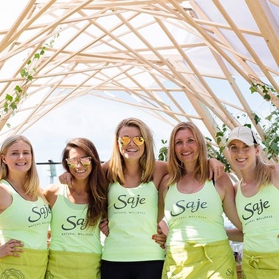 Saje employees wearing Saje branded shirts standing together for a picture outside