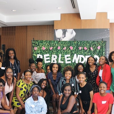 Group photo of BeBlended female employees infront of a greenery backdrop that spells out BeBlended.
