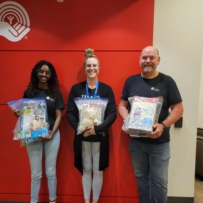 Three United Way employees and co-op students holding donation packages for kids