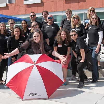 United Way WRC team posing with a branded umbrella outside for a group photo