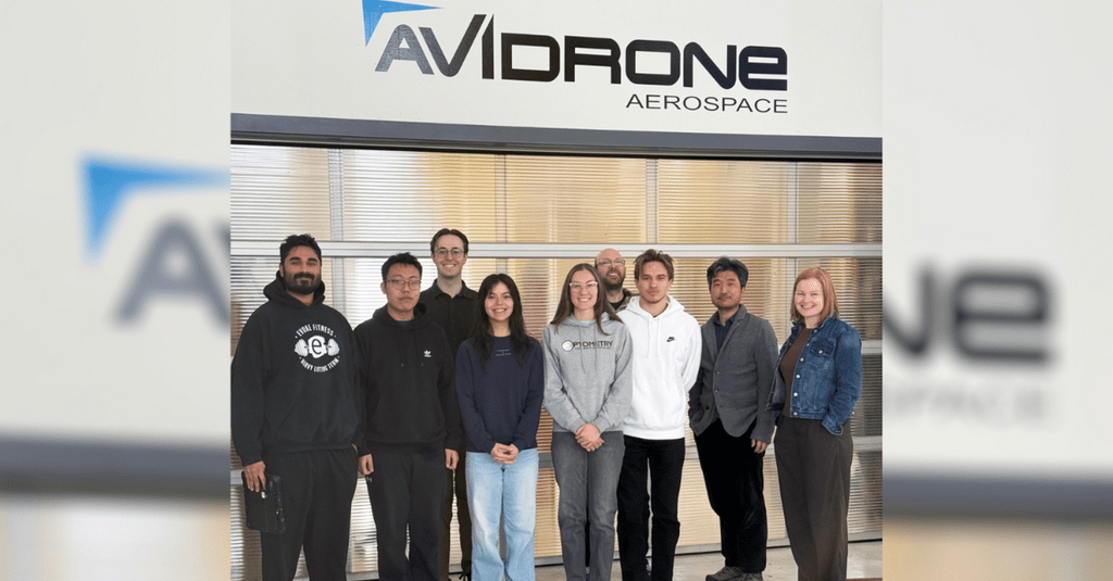 A group of students posing in front of Avidrone logo