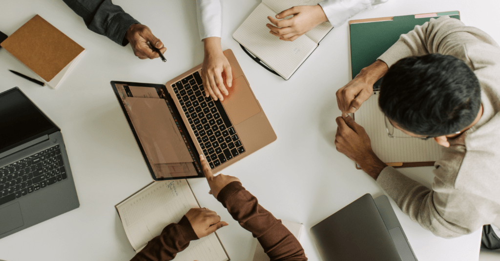 Birds eye view of table with laptop and people.