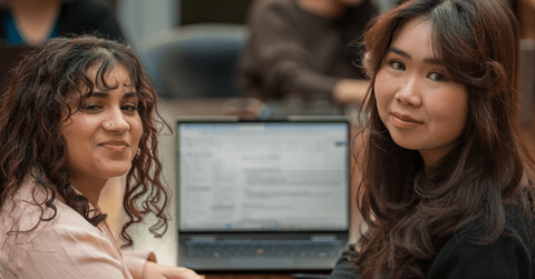 two women sitting at a laptop