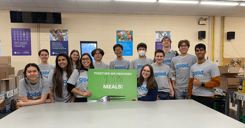 Group of Definity co-op students and employees holding a sign saying they provided 1,588 meals at the food bank