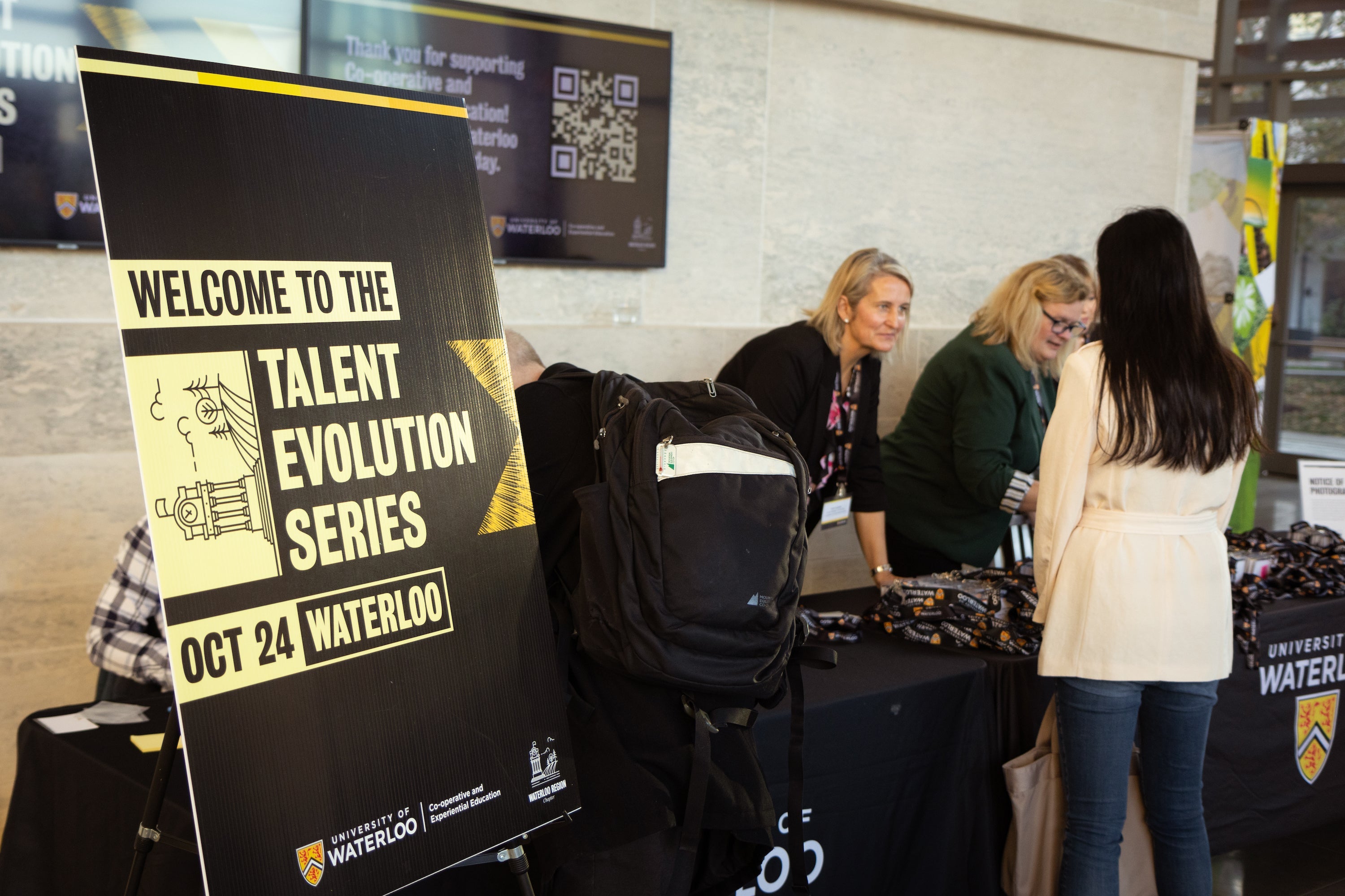 UWaterloo employees working at a booth next to Talent Evolution signage