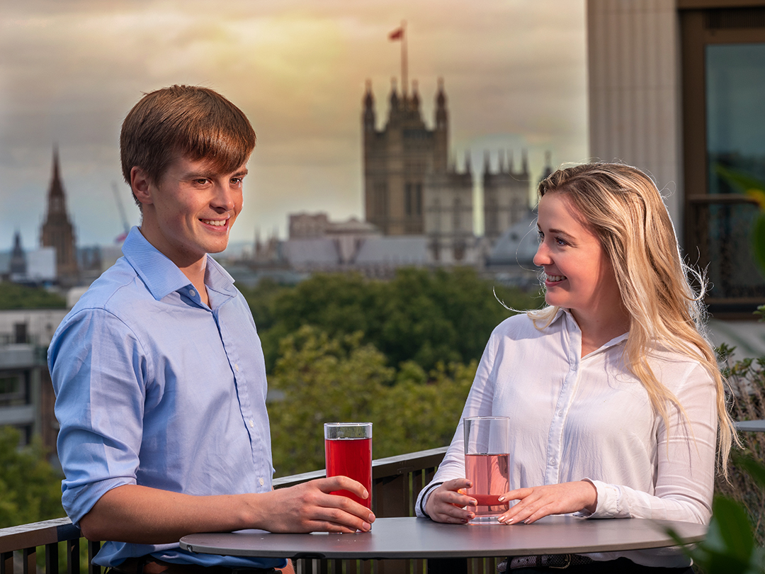 Two Capula Investment co-op students enjoying a drink outside with a parliament building behind them in the distance