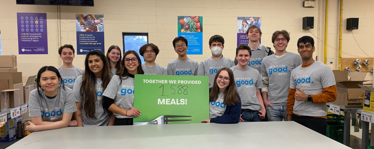 Group of Definity co-op students and employees holding a sign saying they provided 1,588 meals at the food bank