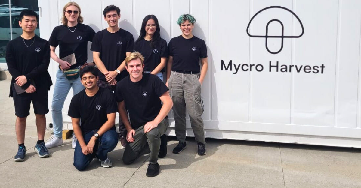 Group of Waterloo co-op students and staff smiling and standing in front of Mycro Harvest labelled shipping container