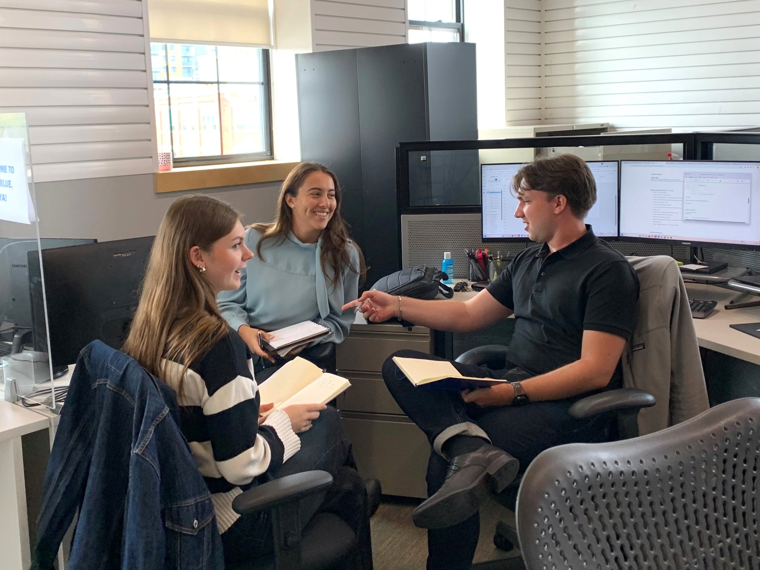 Students sit with a supervisor in an informal meeting setting.