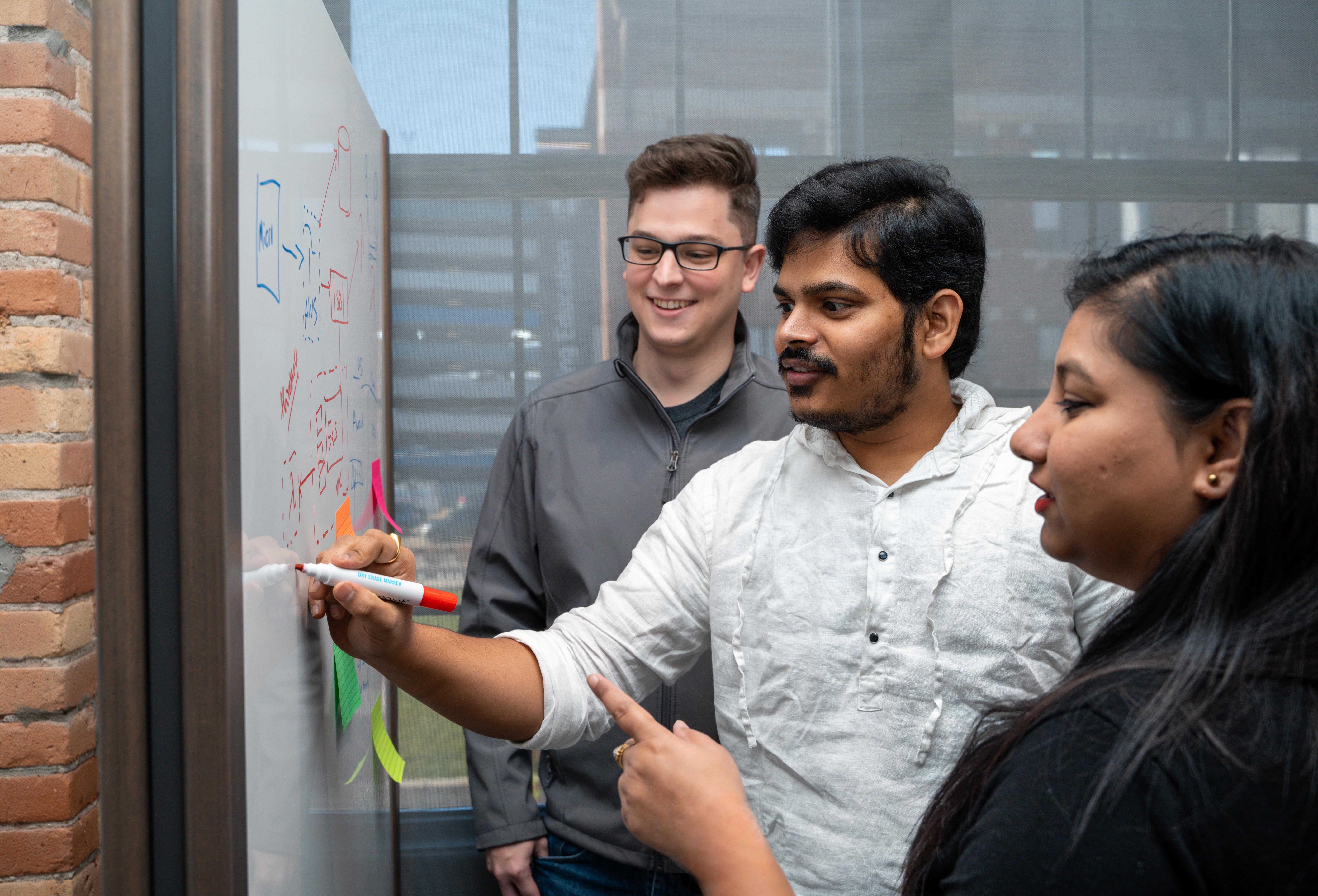 Group of co-op students at Rocket Innovation writing on a white board