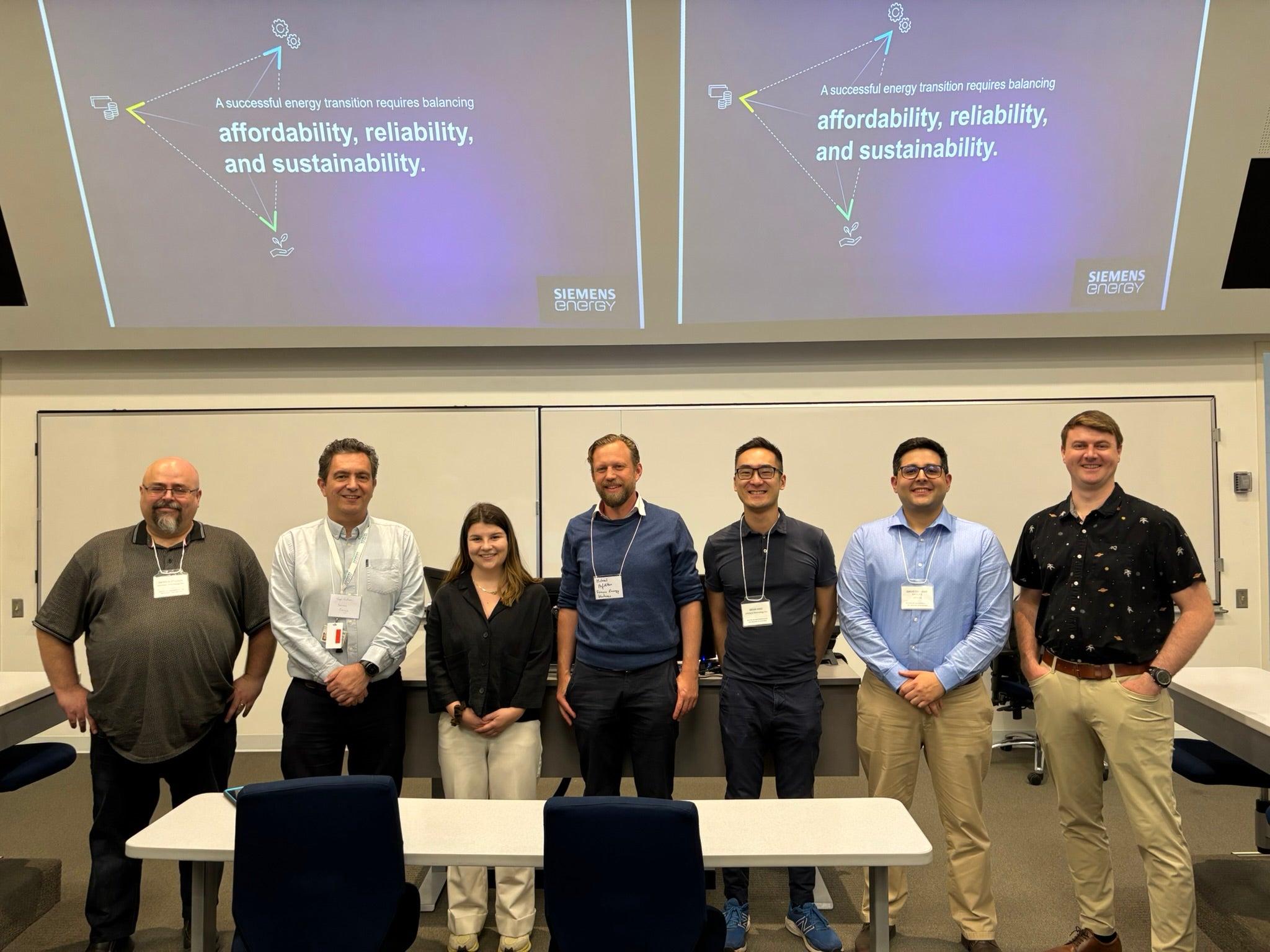 InfinityQ team stands in front of a powerpoint presentation at a conference.