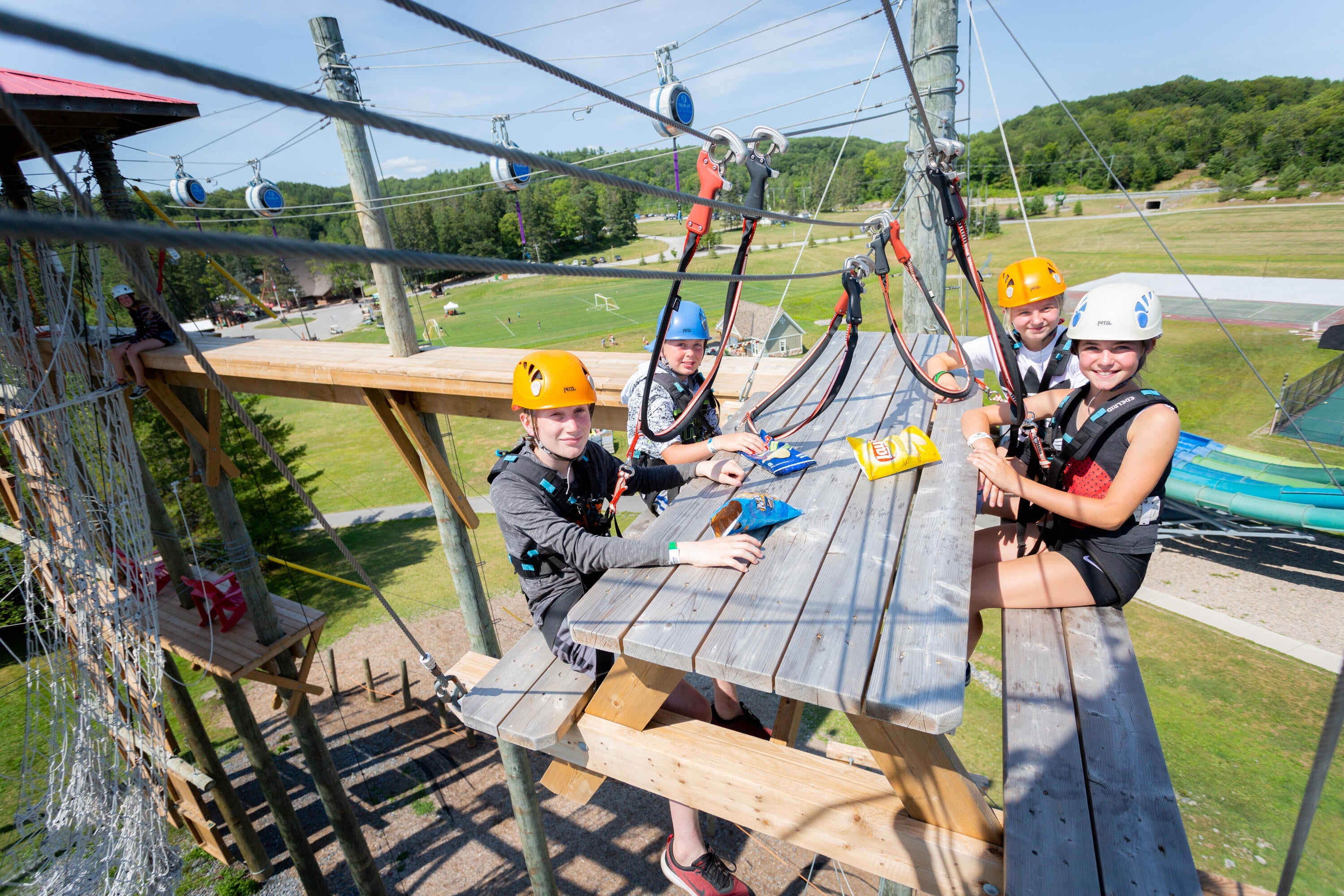 Campers sitting on zip-line picnic bench at Muskoka Woods camp in the summer