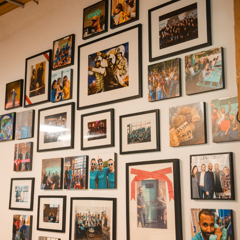 A wall with images of various Loopio employees at different team building activities