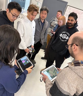 Group of students looking at tablets that control heavy-lift, long-haul cargo drones