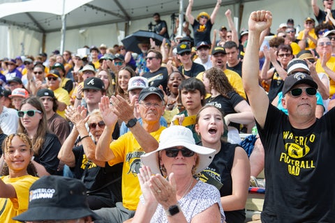 People in football stands cheering at the game