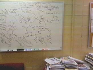 White board with chemical structures and equations.