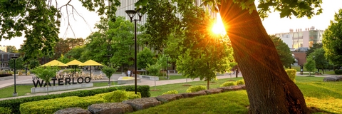 University of Waterloo sign surrounded by greenery during sunset