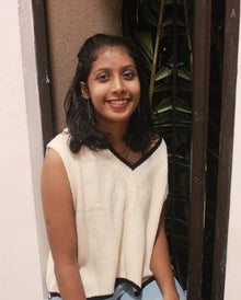 Anamika, a young woman with dark hair, smiles at the camera.