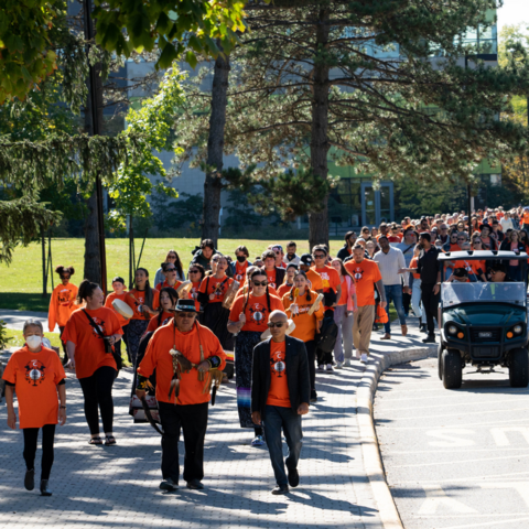 A large group of people wearing orange shirts and walking on ring road