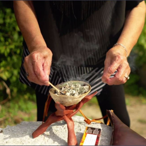 Hands lighting sacred medicines to begin a smudge