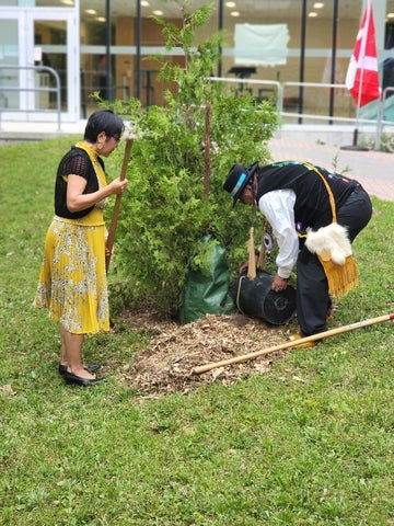 Myeengun Henry and Lili Liu plant a cedar tree