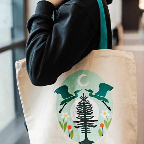 A student holding a bag over their shoulder with Indigenous art work printed on the tote bag