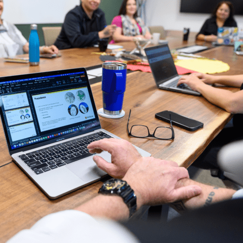 Staff members seated at a boardroom table using a laptop.