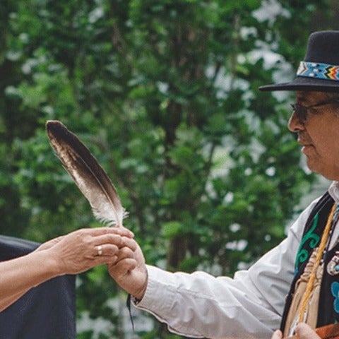 An Elder handing an Eagle feather to a woman