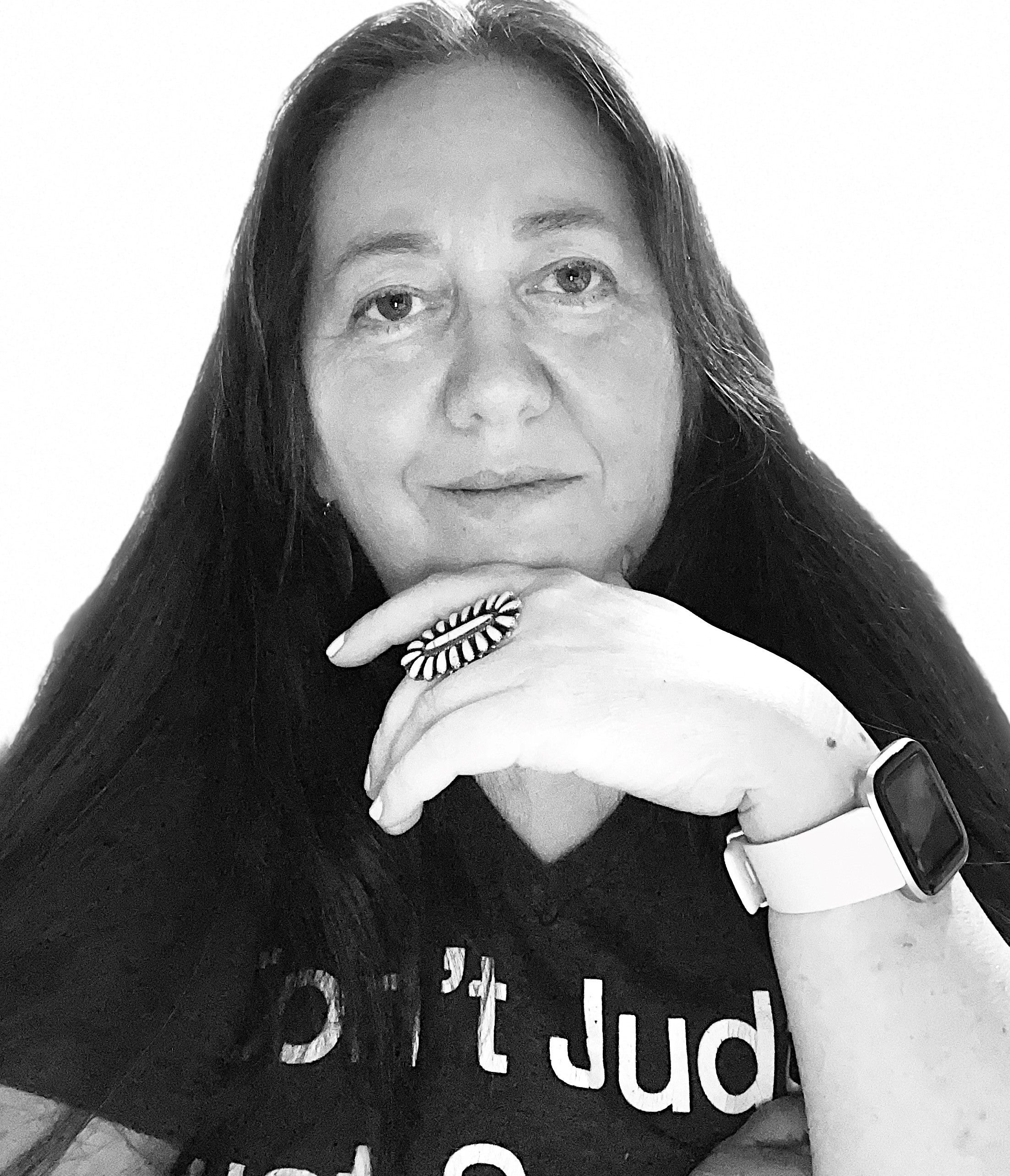 Person with long hair wearing a 'Don't Judg' shirt, a ring on the left hand, and an Apple Watch on the right wrist; face is blurred
