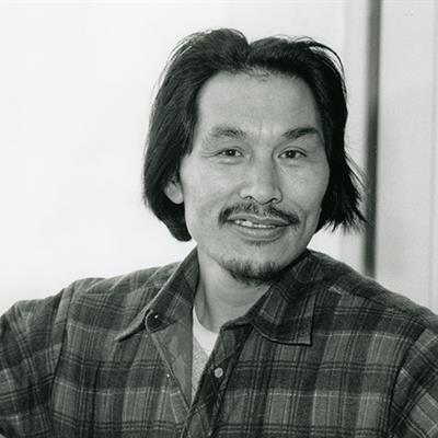 Person in a plaid shirt with a blurred face against a plain light-colored background