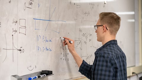 Student working on equations in the photonics lab