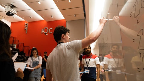 A USEQIP student writing on a whiteboard at the front of IQC's lecture theatre