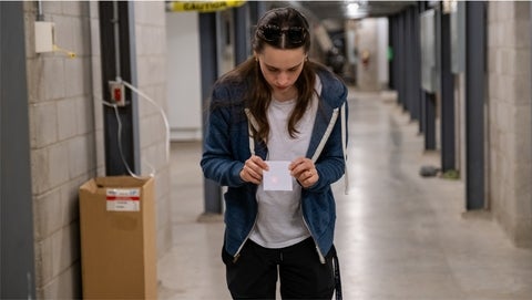 Alex Maierean testing a laser's alignment with a piece of paper at the end of a hallway