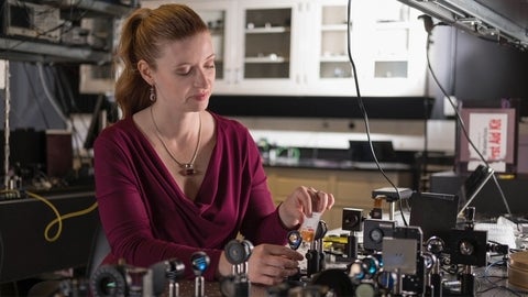 Red haired women in photonics lab working on an optic table