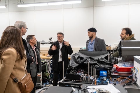 Thomas Jennewein explaining equipment in his lab to five other people