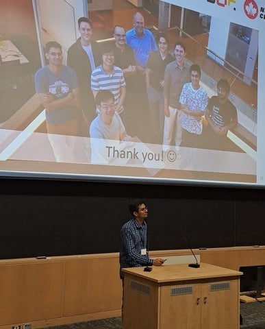 Devashish presenting in Ottawa. Research group pictured in the background.
