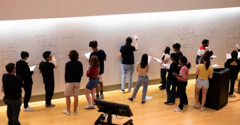 IQC Students writing math equations on a board