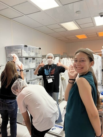 USEQIP students getting ready to enter the clean room by putting on hair nets and shoe covers in the first step
