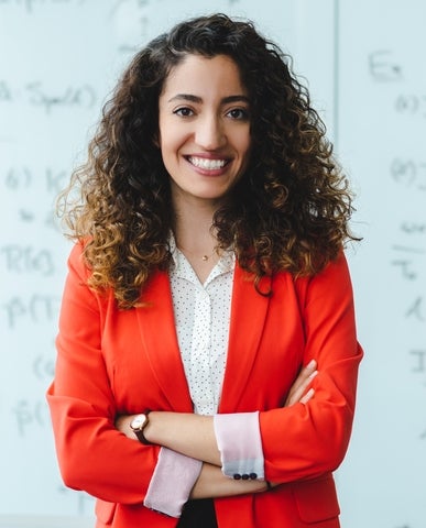 student in blazer, smiling with arms crossed