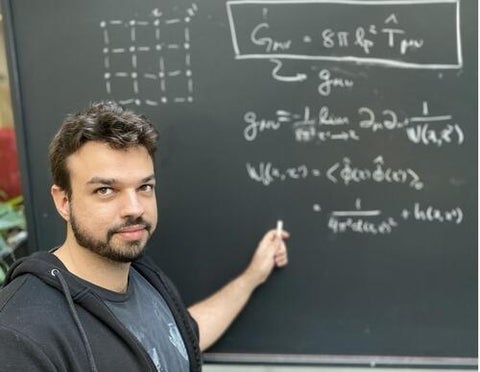 Tales Rick Perche in front of a chalkboard with equations on it