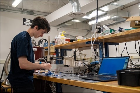 A USEQIP student at a lab bench connecting wires to a measurement apparatus
