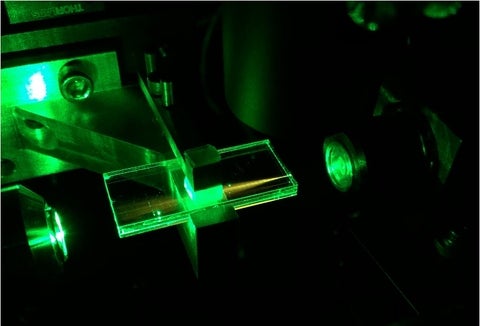 The glass waveguide chip directing green laser light through it