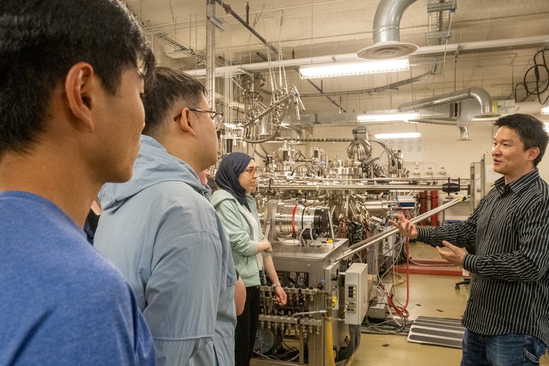 A man speaks to a group of young students in a quantum lab