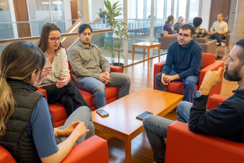 A group of five people sitting in red chairs