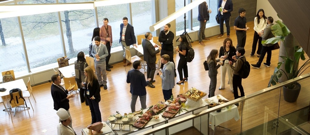 Attendees of the THE summit on the main event reception floor standing and speaking in small groups